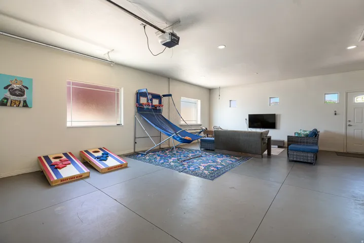 Spacious Garage epoxy -floored area featuring multiple windows, recessed lighting, and a white entry door with frosted glass