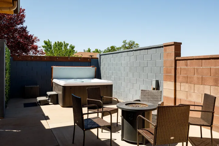 Outdoor patio featuring a built-in spa, a fire pit, and durable block wall fencing