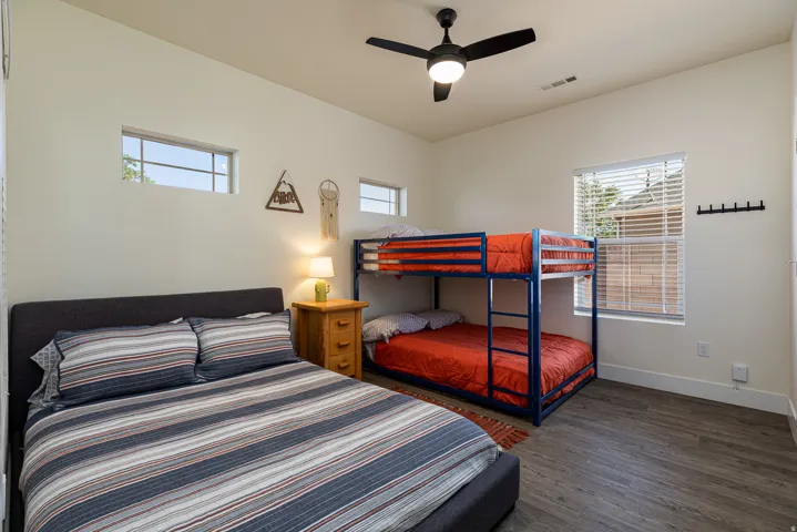 Spacious room featuring wood-finish flooring, a contemporary ceiling fan, and ample natural light from multiple windows