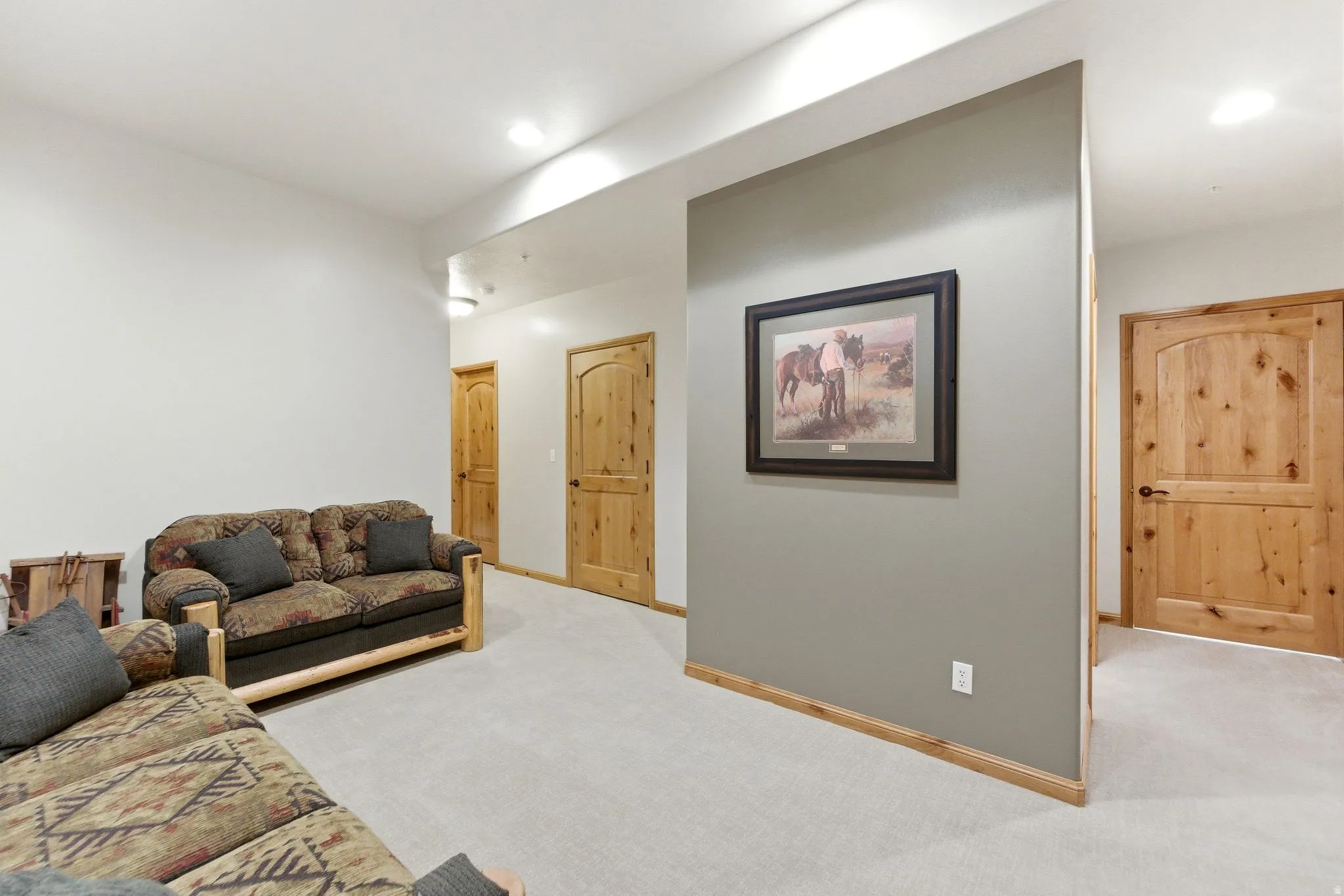 Carpeted interior space featuring light-colored walls, recessed lighting, and multiple wood-panel doors with dark hardware