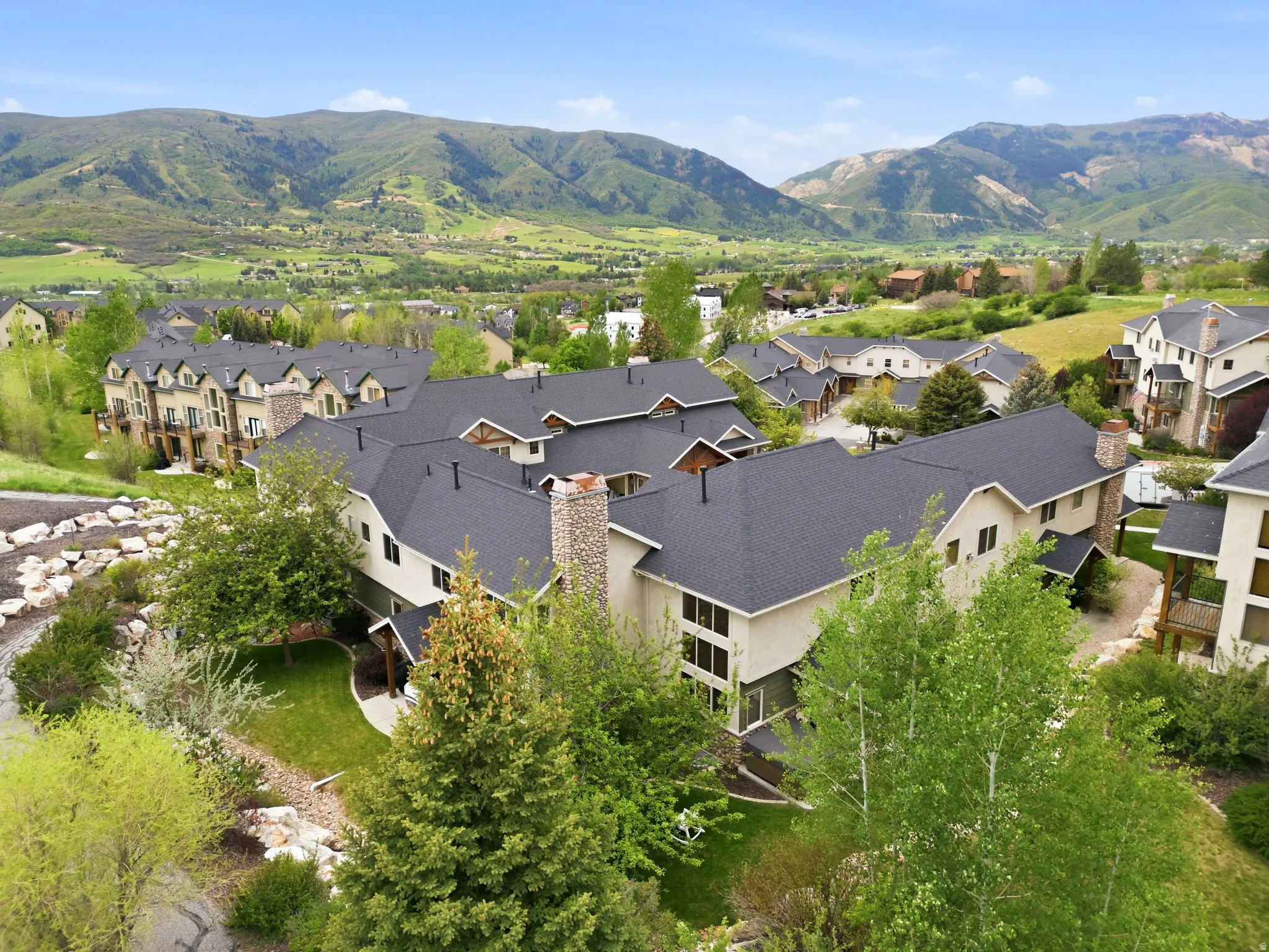 Expansive residential community featuring multiple buildings with dark shingle roofs, light-toned siding, and stone chimney accents