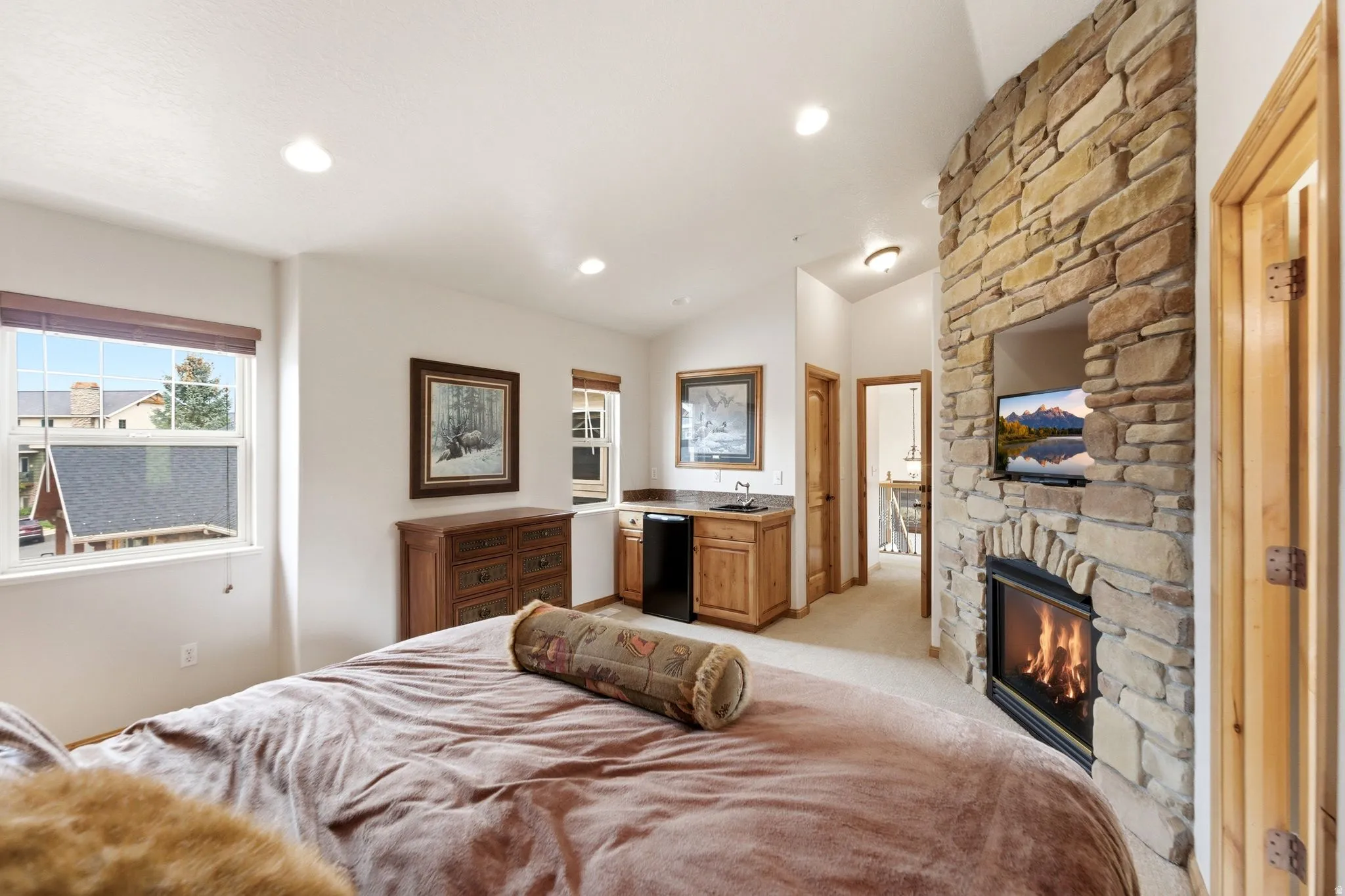 Stone-clad fireplace with integrated media niche and built-in mini-bar with sink and cabinetry
