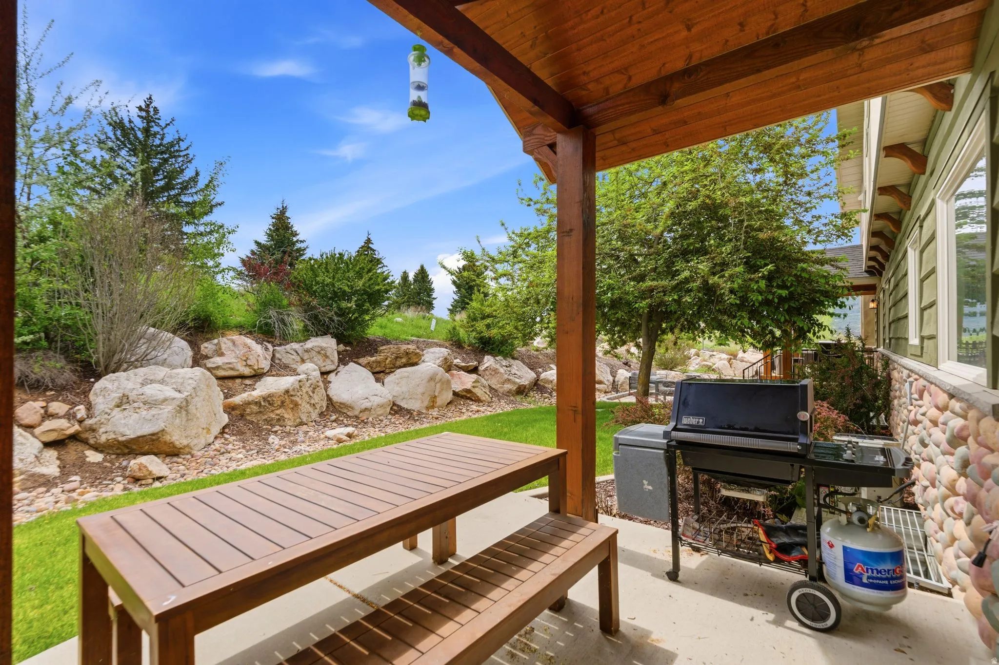 Covered patio with a concrete surface, wooden support beams, and tongue-and-groove ceiling