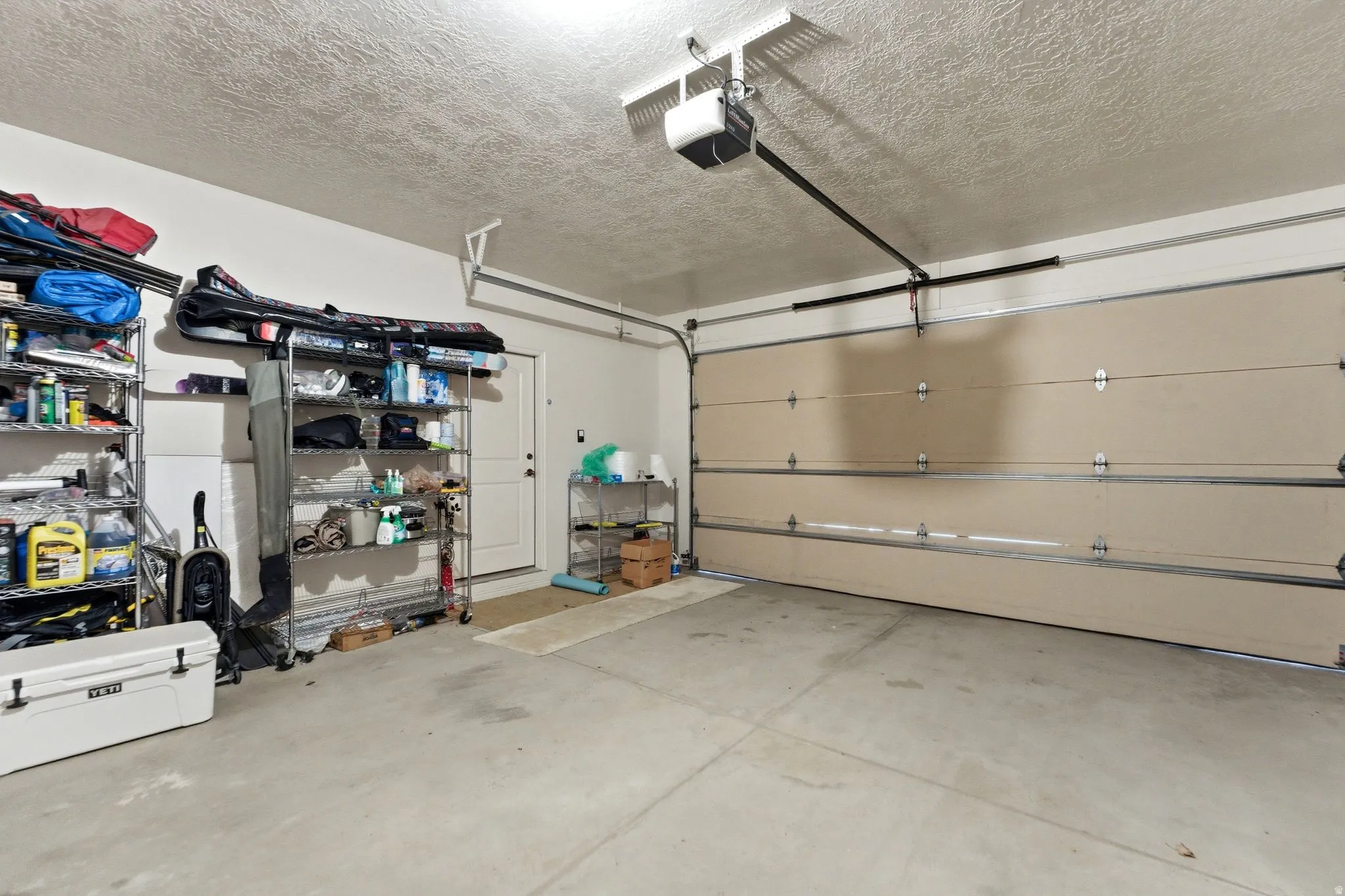Two-car garage featuring a sectional garage door, concrete flooring, and a ceiling-mounted garage door opener