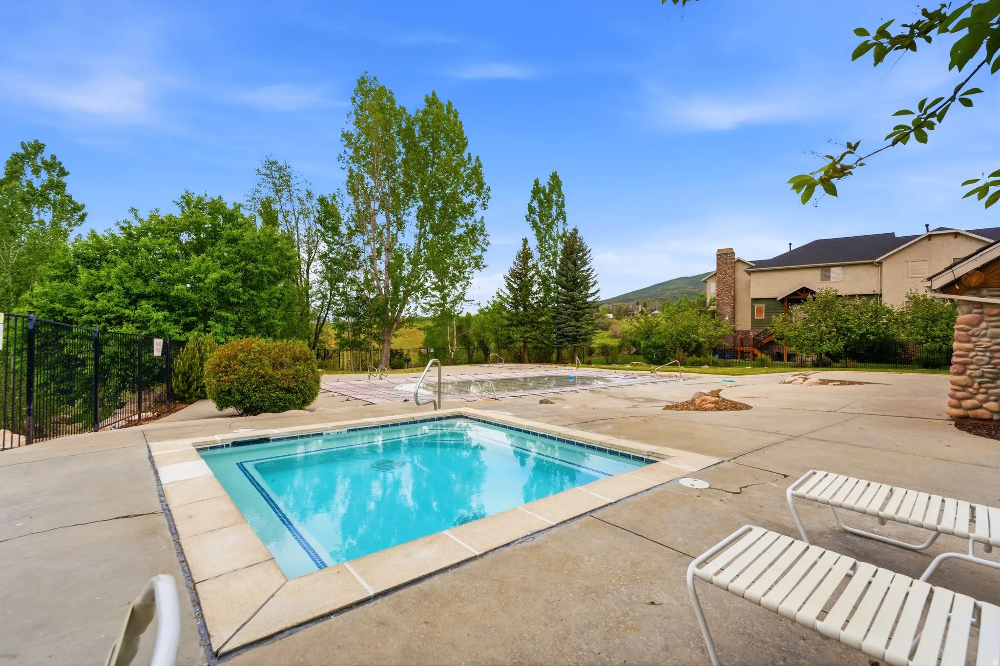 Concrete patio surrounding a square spa with tiled trim