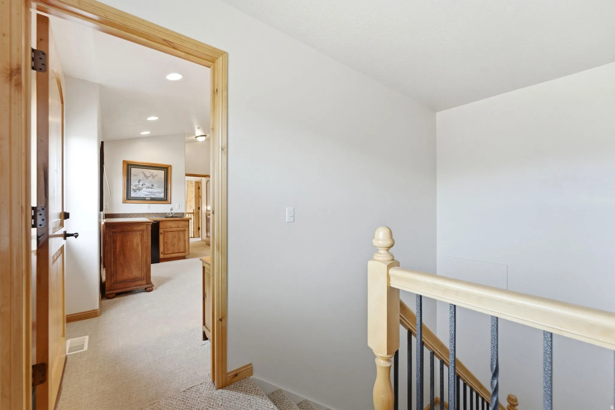 Interior wood door and trim opening to a hallway featuring a built-in wet bar with wood cabinetry and a stone-finish countertop