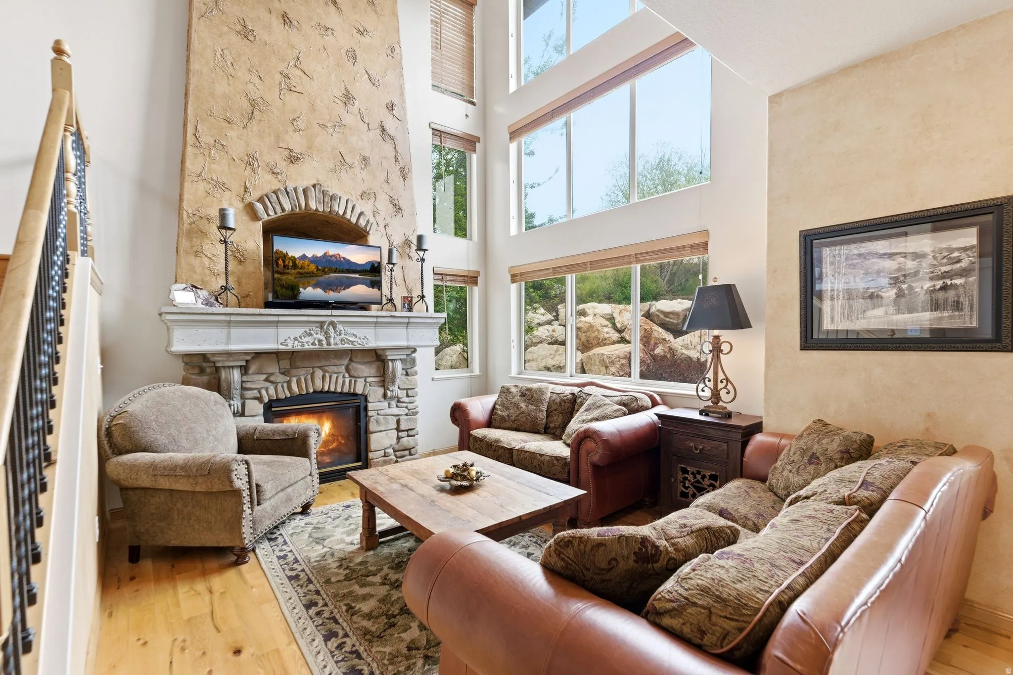 Spacious living area featuring a stone fireplace with a decorative mantel, a textured stucco accent wall, and high ceilings