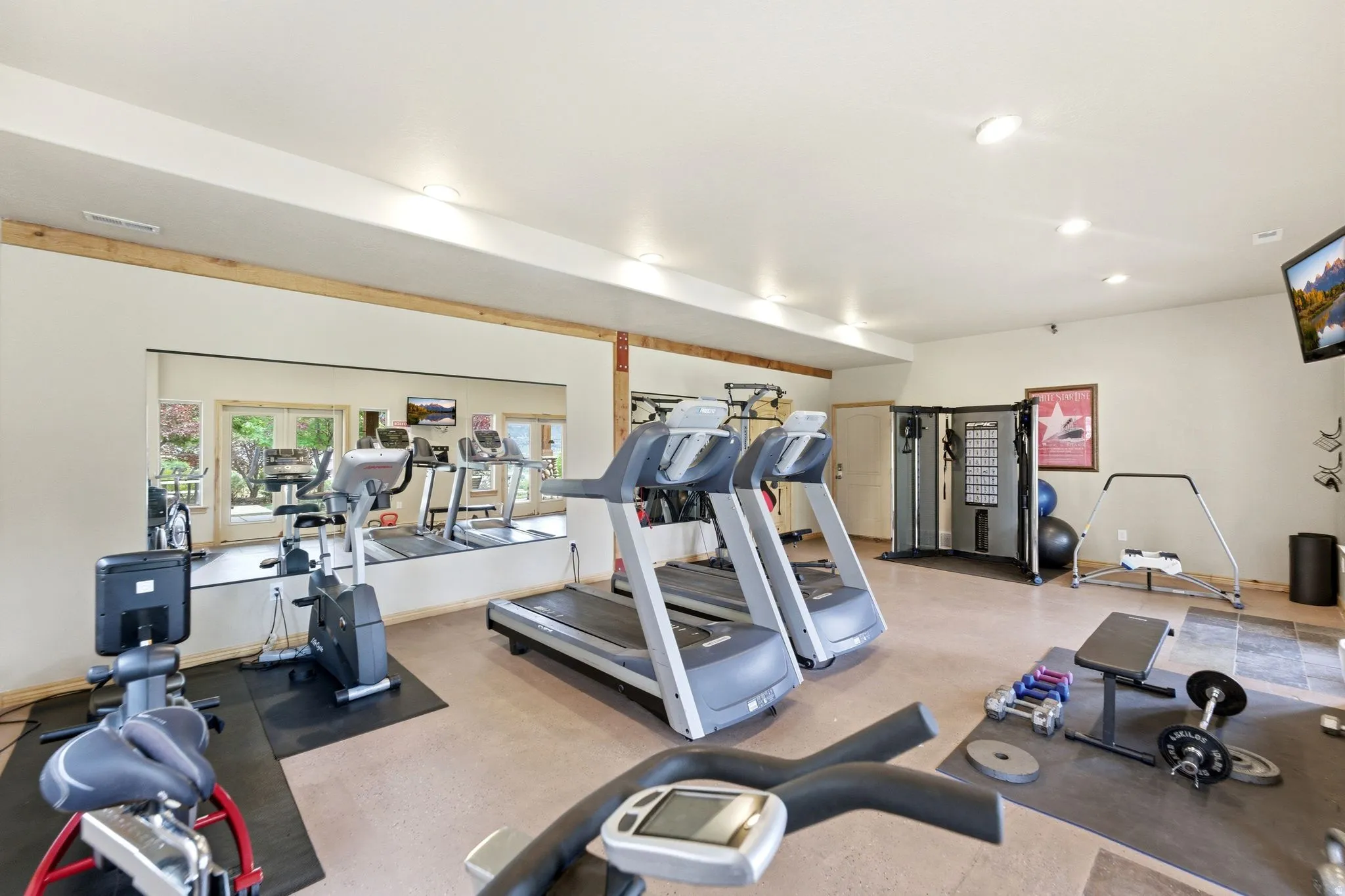 Dedicated fitness area featuring extensive wall mirrors, neutral-toned flooring, recessed lighting, and a built-in multi-gym system