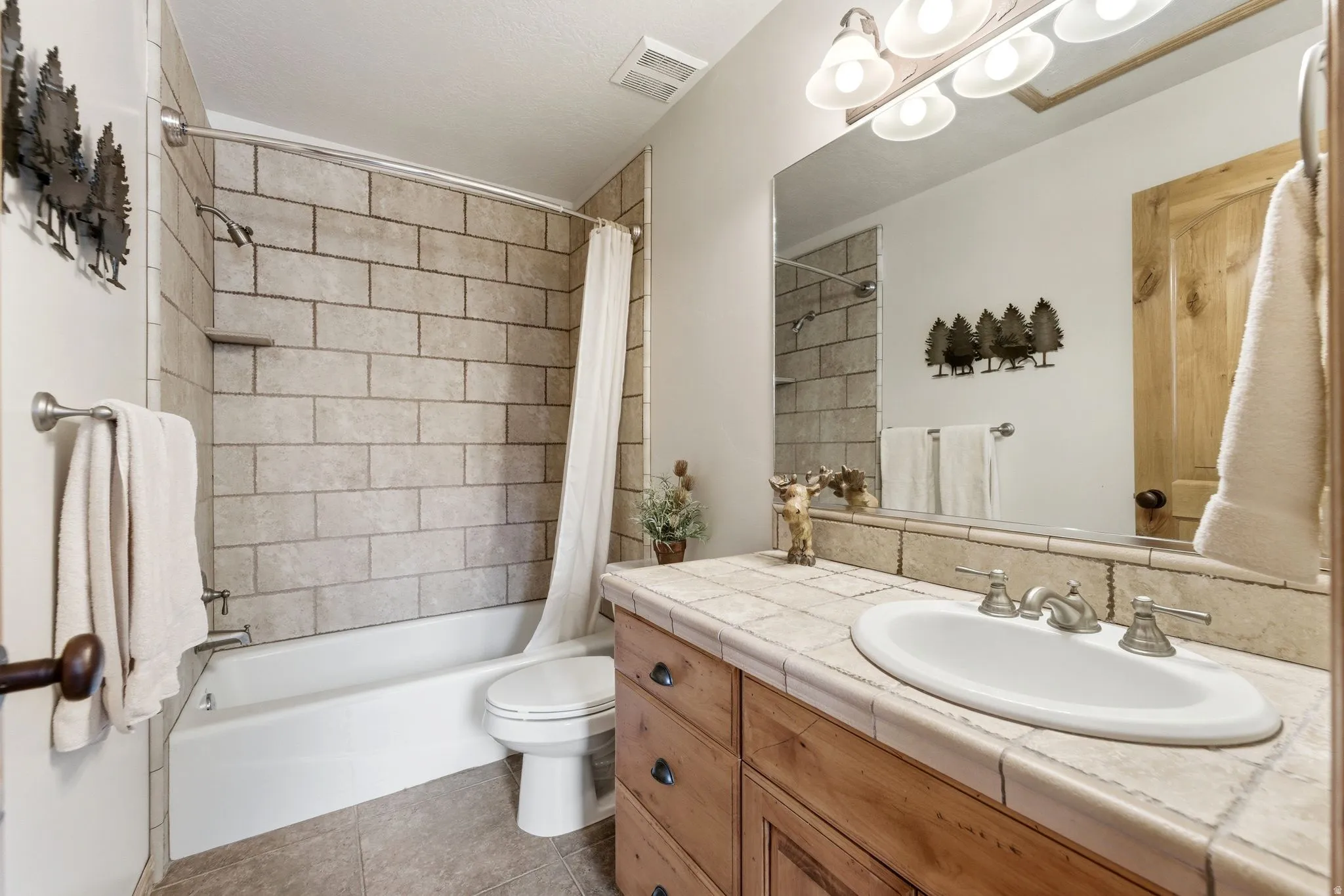 Bathroom featuring a built-in wood vanity with tile countertop, integrated sink, and brushed nickel fixtures
