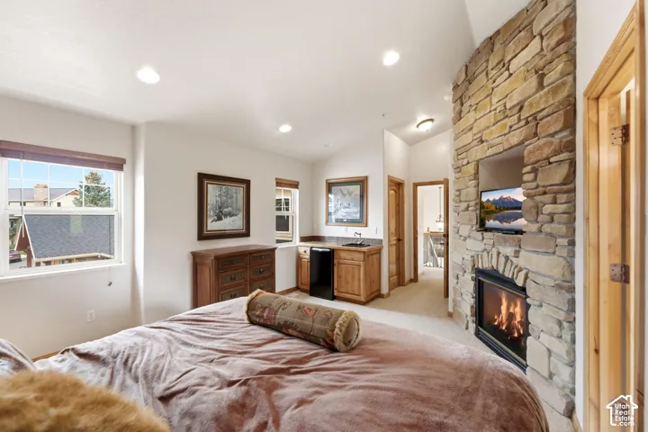 Stone-clad fireplace with integrated media niche and built-in mini-bar with sink and cabinetry