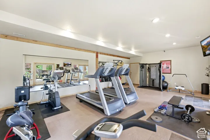 Dedicated fitness area featuring extensive wall mirrors, neutral-toned flooring, recessed lighting, and a built-in multi-gym system