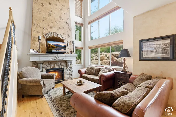 Spacious living area featuring a stone fireplace with a decorative mantel, a textured stucco accent wall, and high ceilings
