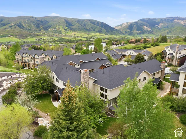 Expansive residential community featuring multiple buildings with dark shingle roofs, light-toned siding, and stone chimney accents