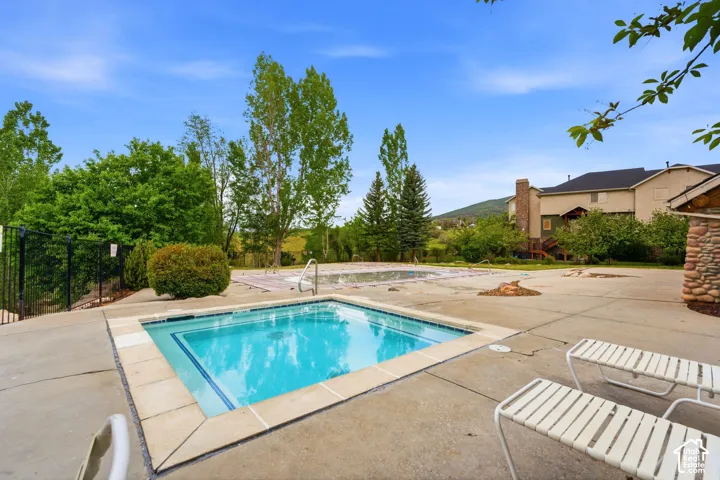 Concrete patio surrounding a square spa with tiled trim