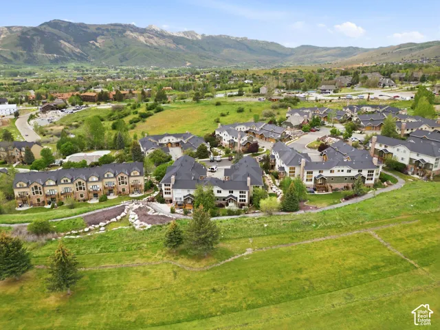 Expansive hillside community featuring multiple multi-story townhome-style residences with dark roofing, light-toned siding, and surrounding green spaces