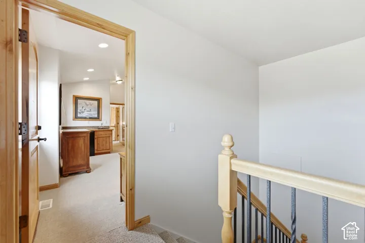 Interior wood door and trim opening to a hallway featuring a built-in wet bar with wood cabinetry and a stone-finish countertop