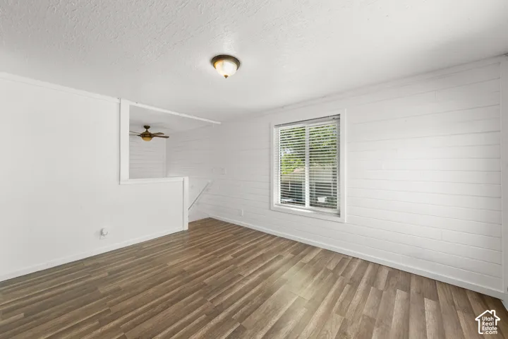 Wood-finish flooring with white shiplap walls and a double-hung window with blinds
