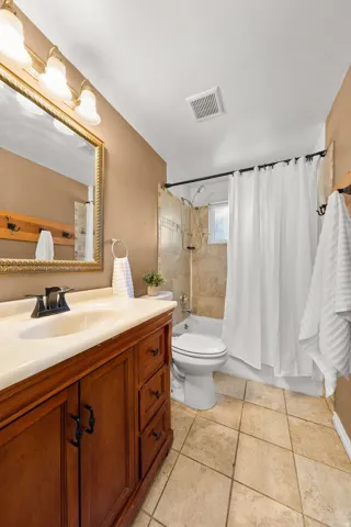 Wood-finish vanity with an integrated sink, polished countertop, and tile flooring