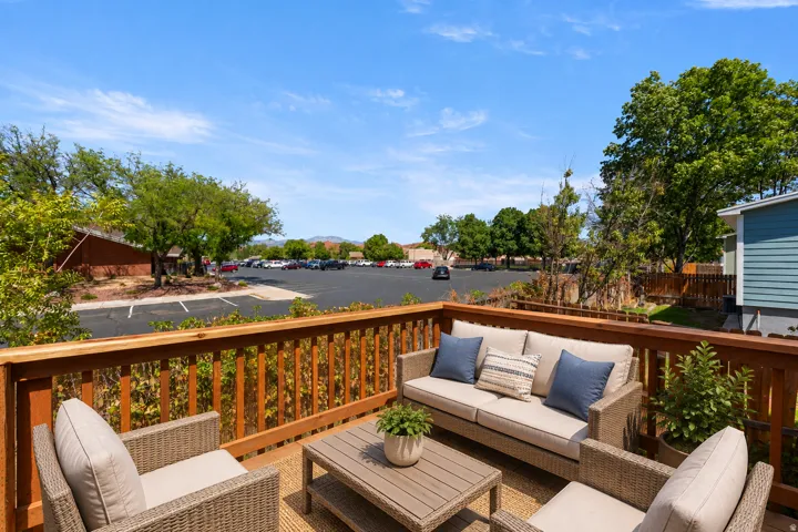 Expansive wood-finish deck with a wood railing and a parking area beyond