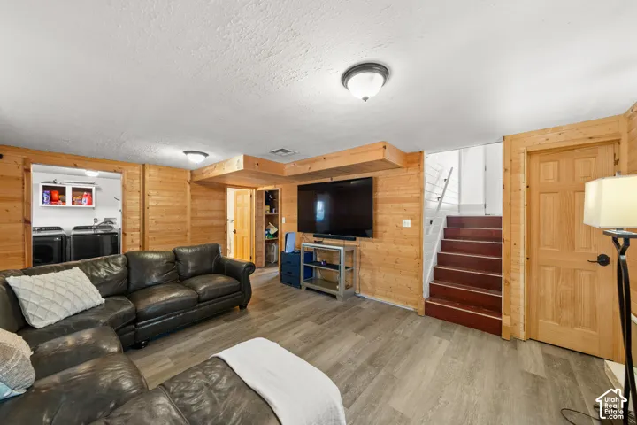 Light wood-finish paneling, wood-finish flooring, recessed ceiling lighting, and a built-in laundry area with overhead cabinetry