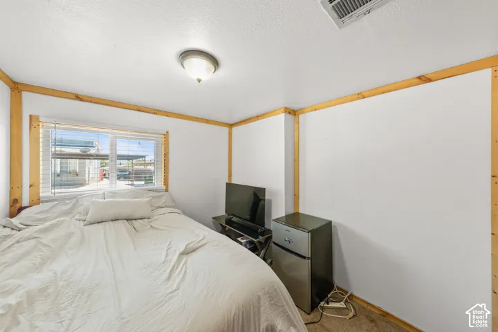 White walls with natural wood trim accents, a window with horizontal blinds, and a flush-mount ceiling light fixture