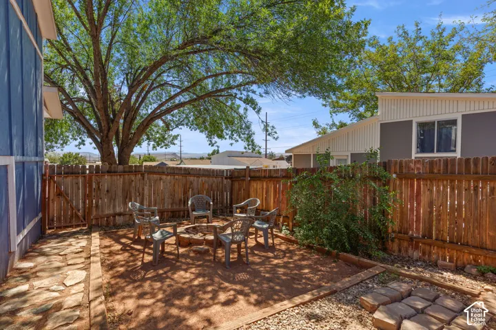 Enclosed backyard featuring a fire pit area, natural stone pathway, and mature tree providing shade