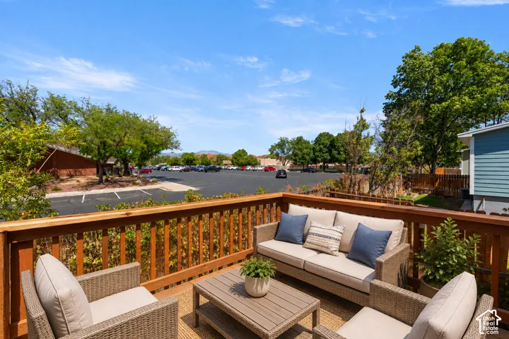 Expansive wood-finish deck with a wood railing and a parking area beyond