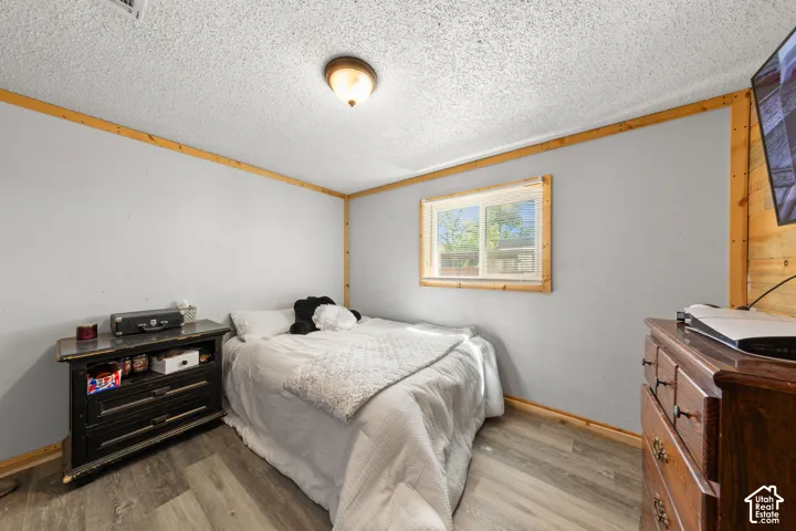 Wood-finish flooring, light grey painted walls, natural wood trim, and a window for natural illumination