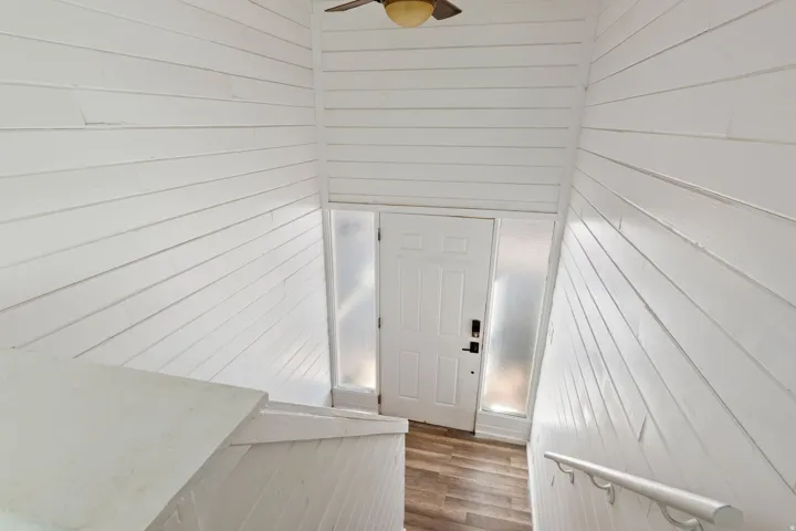 Entryway featuring a white paneled door with frosted glass sidelights, wood-finish flooring, and white shiplap walls
