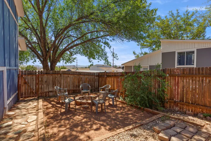 Enclosed backyard featuring a fire pit area, natural stone pathway, and mature tree providing shade