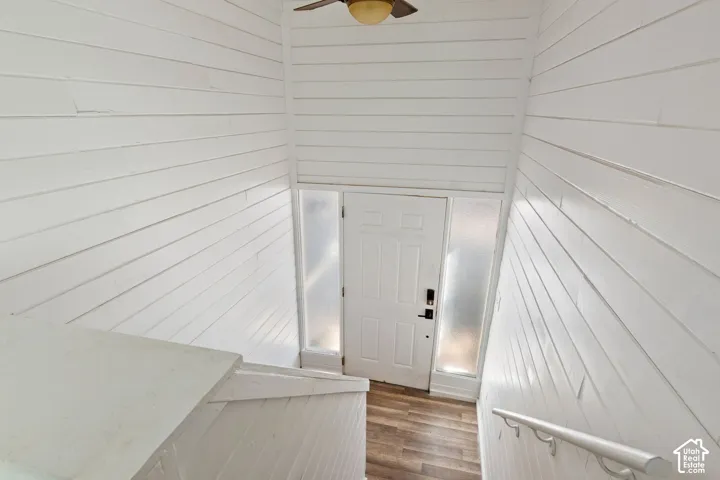 Entryway featuring a white paneled door with frosted glass sidelights, wood-finish flooring, and white shiplap walls