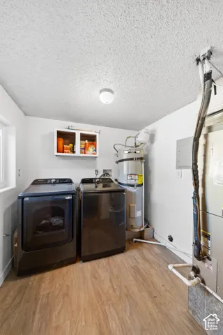 Utility room featuring wood-finish flooring, a wall-mounted cabinet, and a window for natural illumination