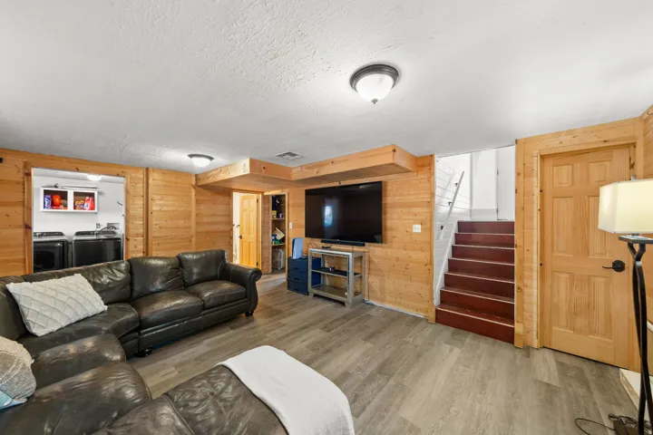 Light wood-finish paneling, wood-finish flooring, recessed ceiling lighting, and a built-in laundry area with overhead cabinetry