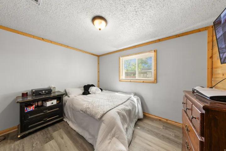 Wood-finish flooring, light grey painted walls, natural wood trim, and a window for natural illumination