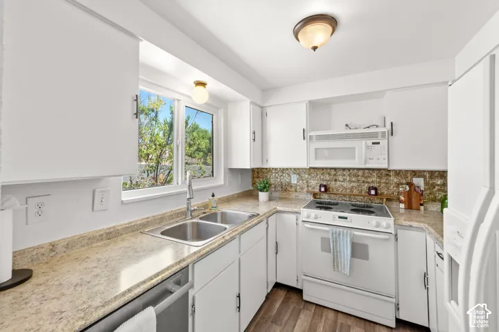 Kitchen featuring white cabinetry, wood-finish flooring, dual basin stainless steel sink, built-in microwave, and an electric range