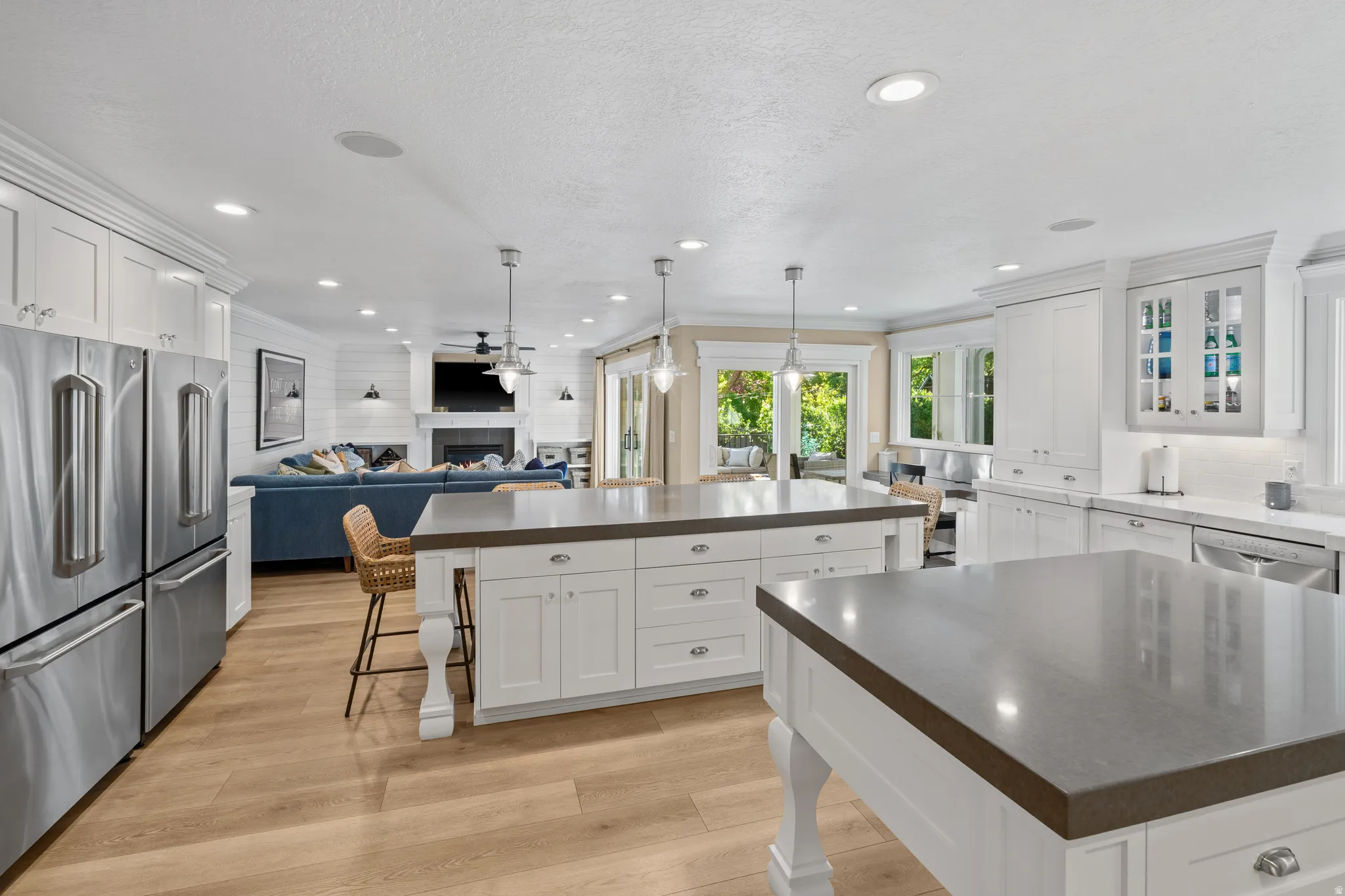 Kitchen featuring two islands with dark countertops, wood-finish flooring, and white cabinetry
