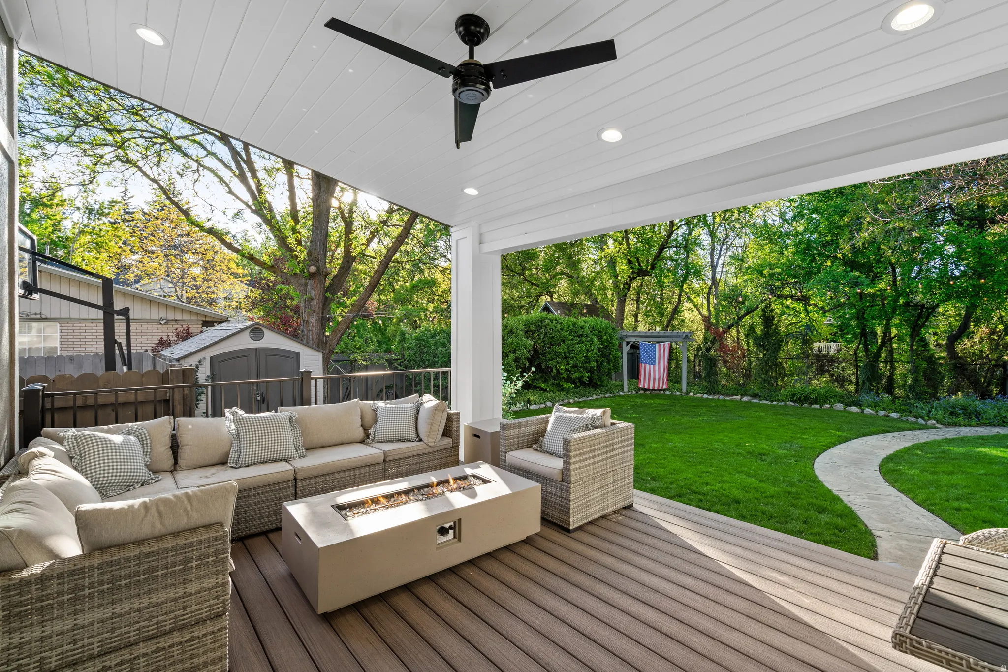 Covered patio featuring a wood-finish composite deck, ceiling fan, recessed lighting, and a fire pit