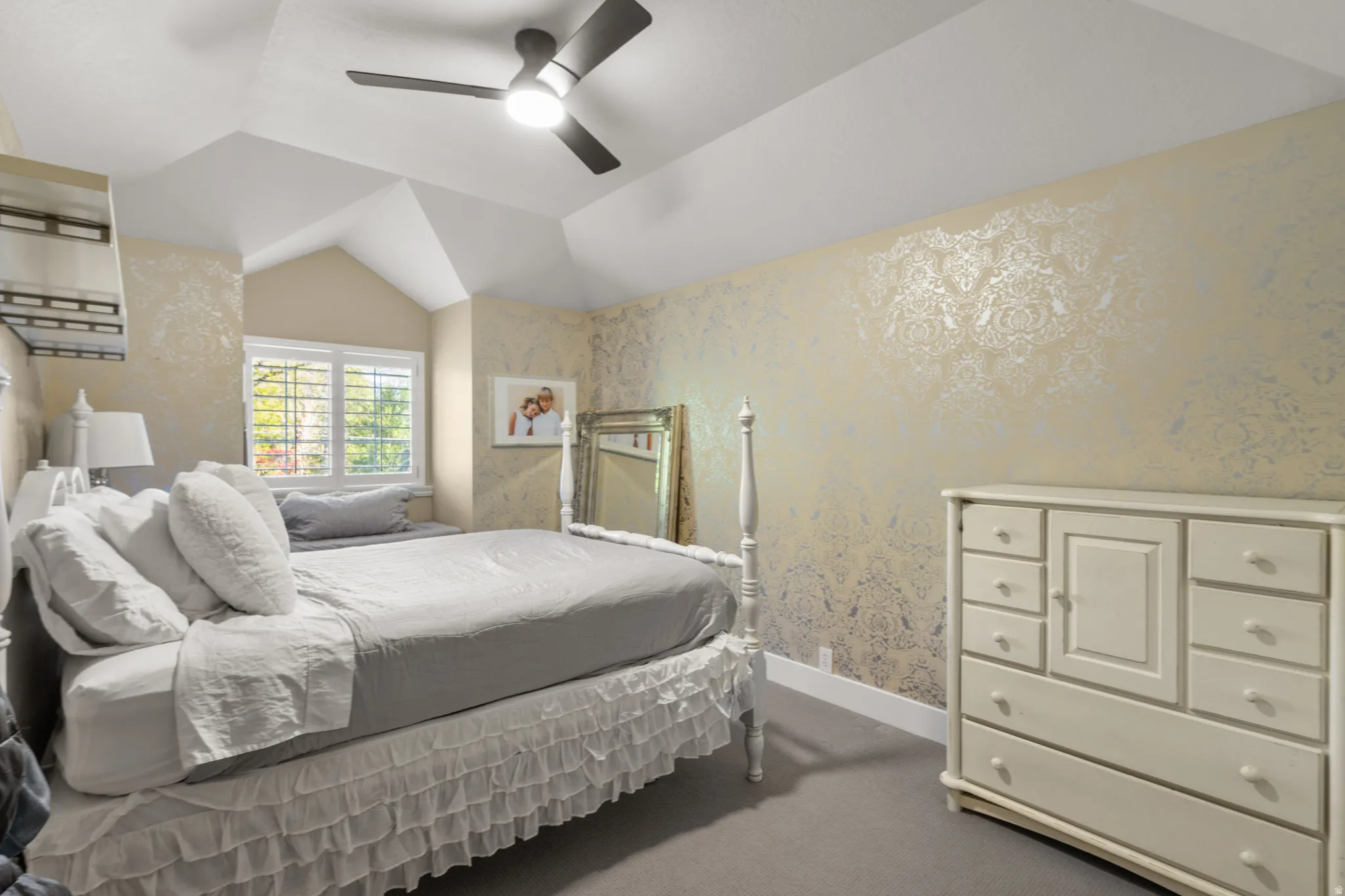 Room featuring a vaulted ceiling with a modern ceiling fan and decorative wall treatment