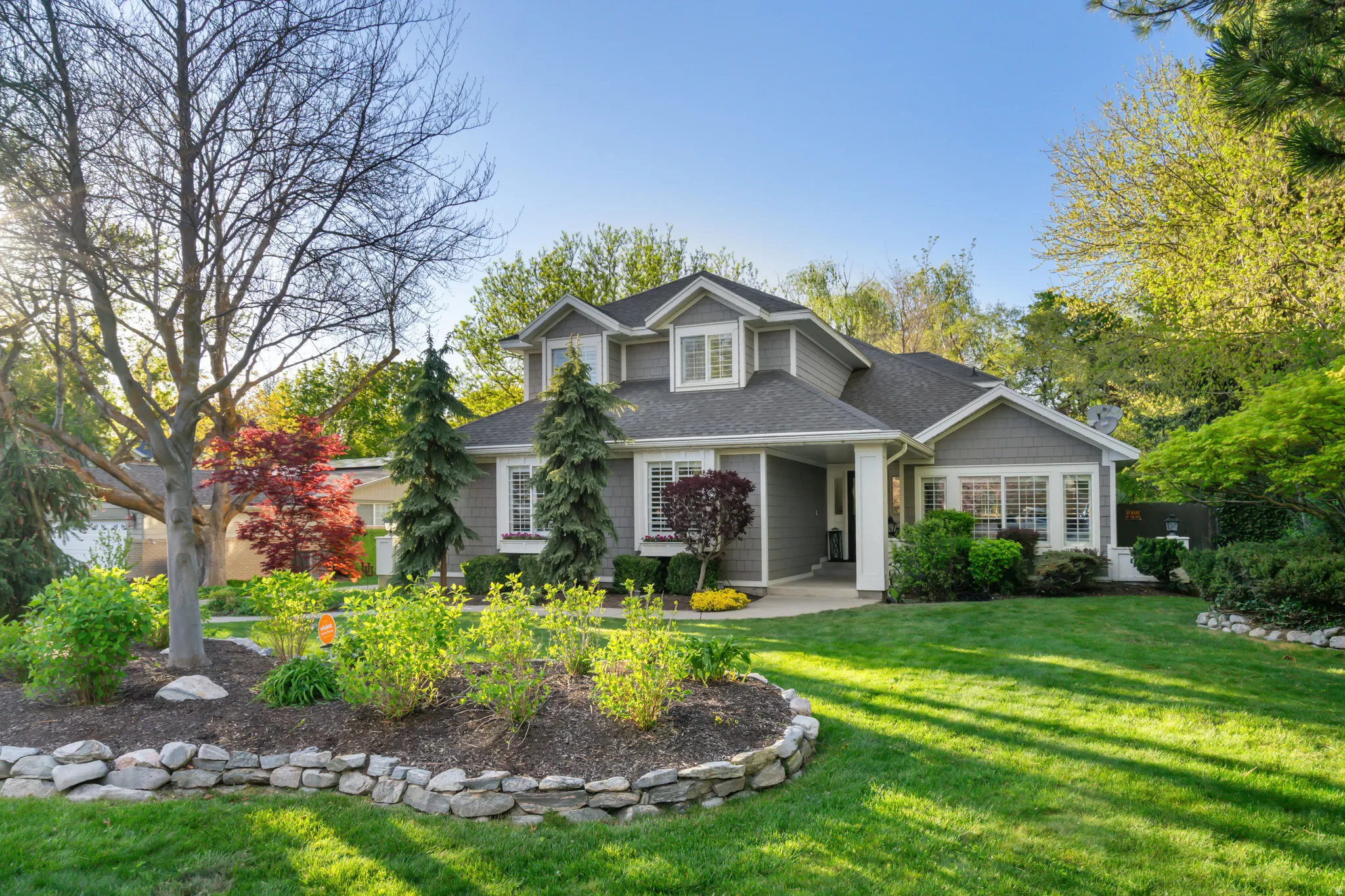 Single-story property featuring gray siding, white trim, multiple gables, and a prominent front entrance with a covered porch