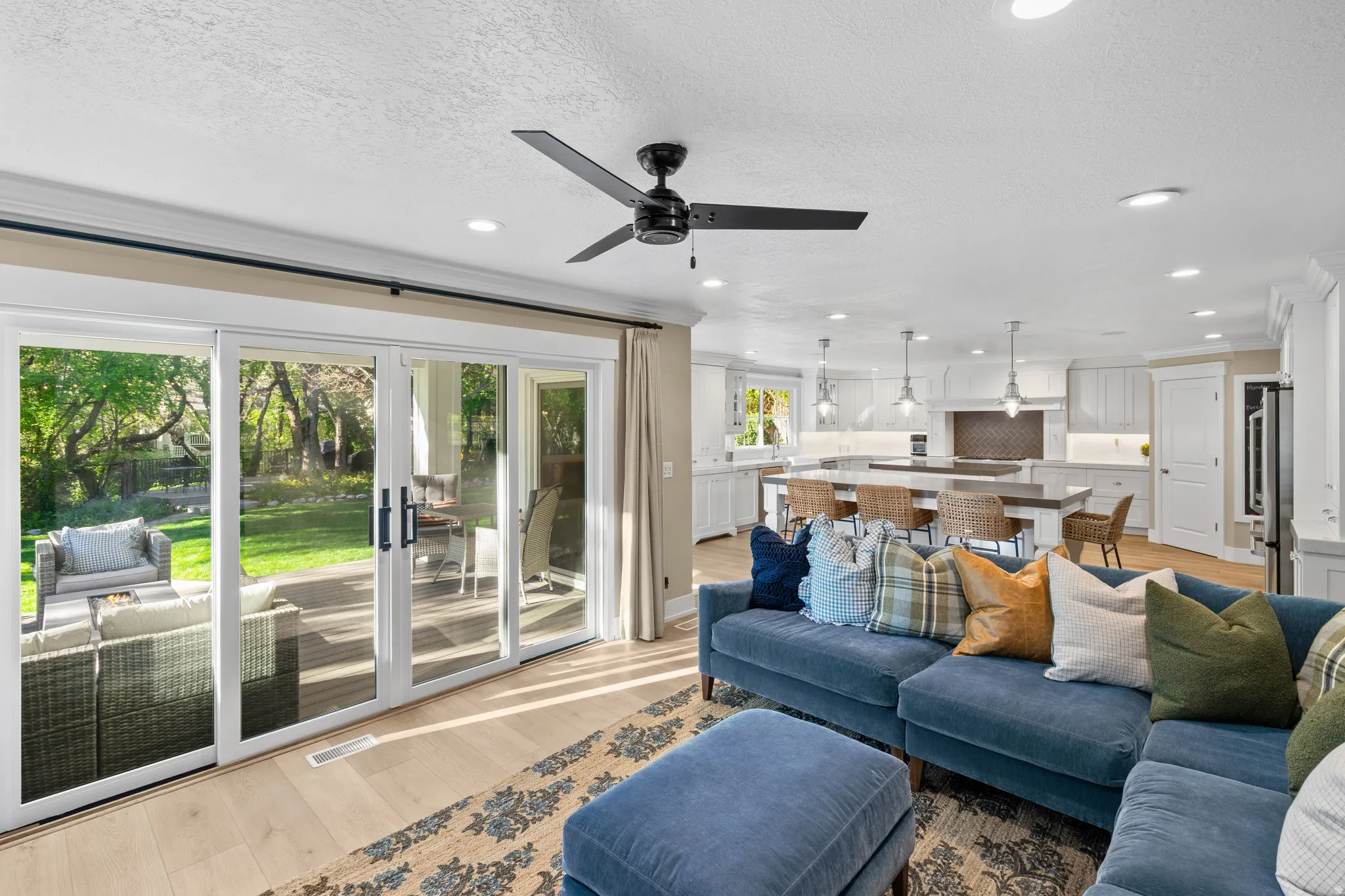Open-concept living area featuring light wood-finish flooring, recessed lighting, and a black ceiling fan