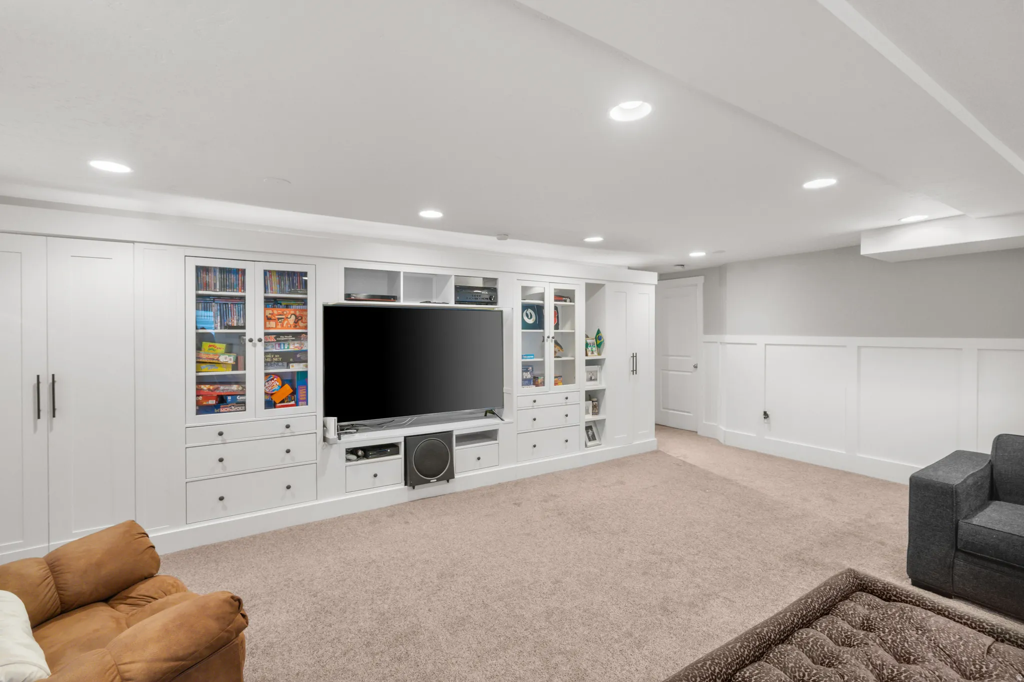 Built-in entertainment center featuring extensive cabinetry, glass-front display cases, integrated shelving, and recessed lighting
