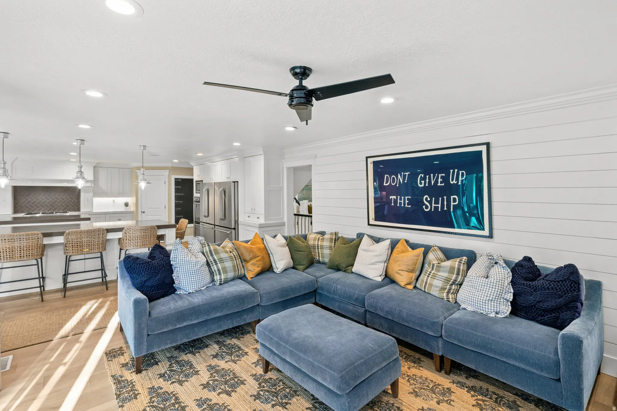Open-concept living area featuring wood-finish flooring, recessed lighting, and a dark-toned ceiling fan