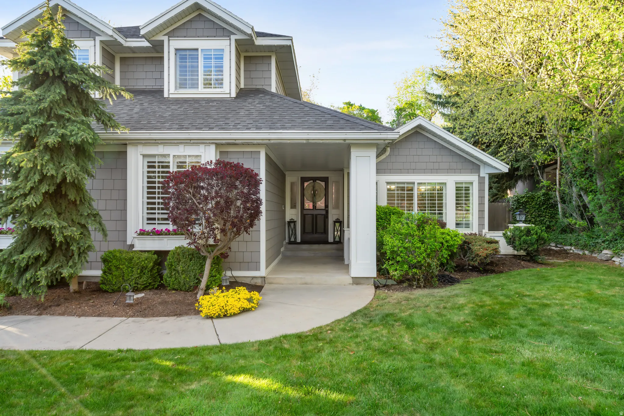 Shingle-sided exterior with white trim, a covered entryway, and a dark front door