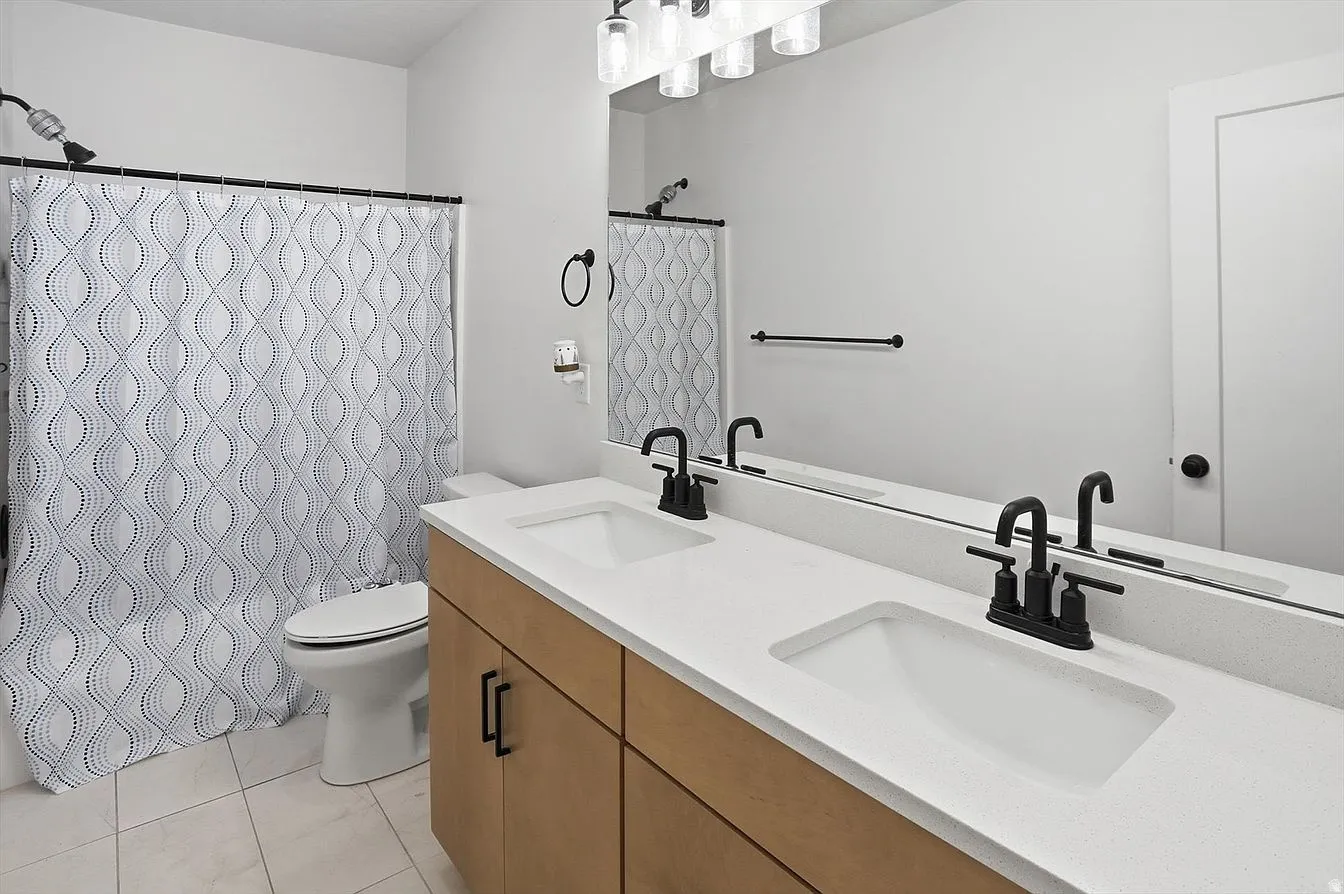 Bathroom featuring a dual vanity with modern white oak design cabinetry.