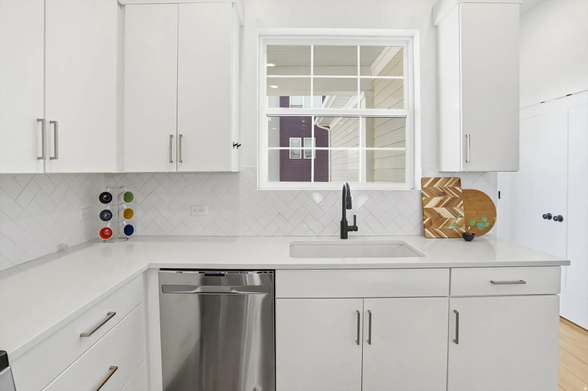 Contemporary kitchen featuring white cabinetry, stainless steel appliances, gas range, two-tone white and oak cabinetry, brass hardware, refined designer finishes, an oversized sink-free island, and walk-in pantry.