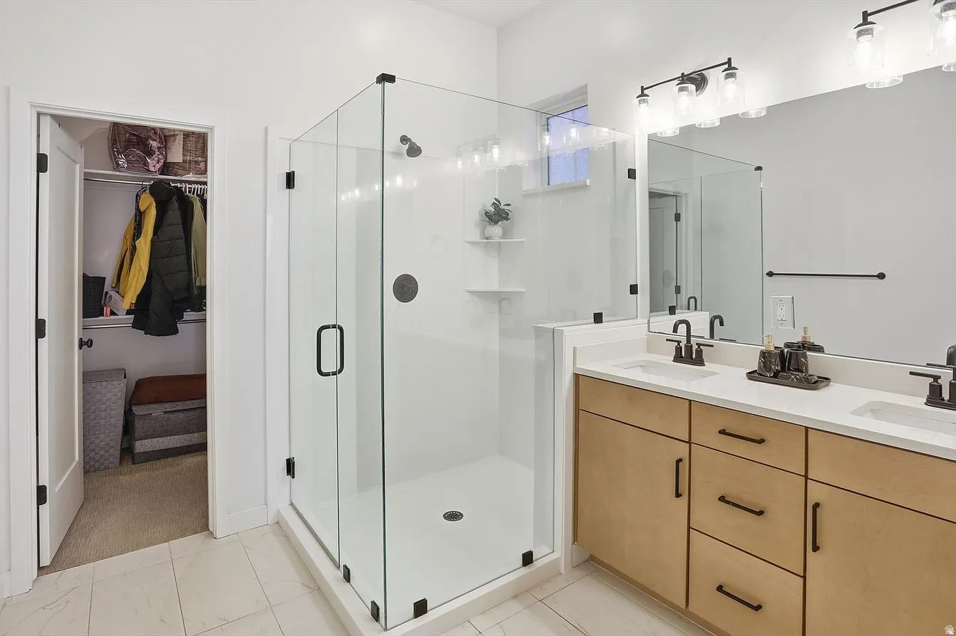 Glass-enclosed shower with matte black hardware. The spa-inspired ensuite bathroom features dual sinks, a Euro glass shower, water closet, and generous walk-in closet.