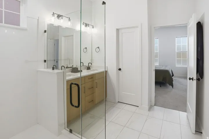 Contemporary spa-inspired ensuite bathroom features dual sinks, a Euro glass shower, water closet, and generous walk-in closet.