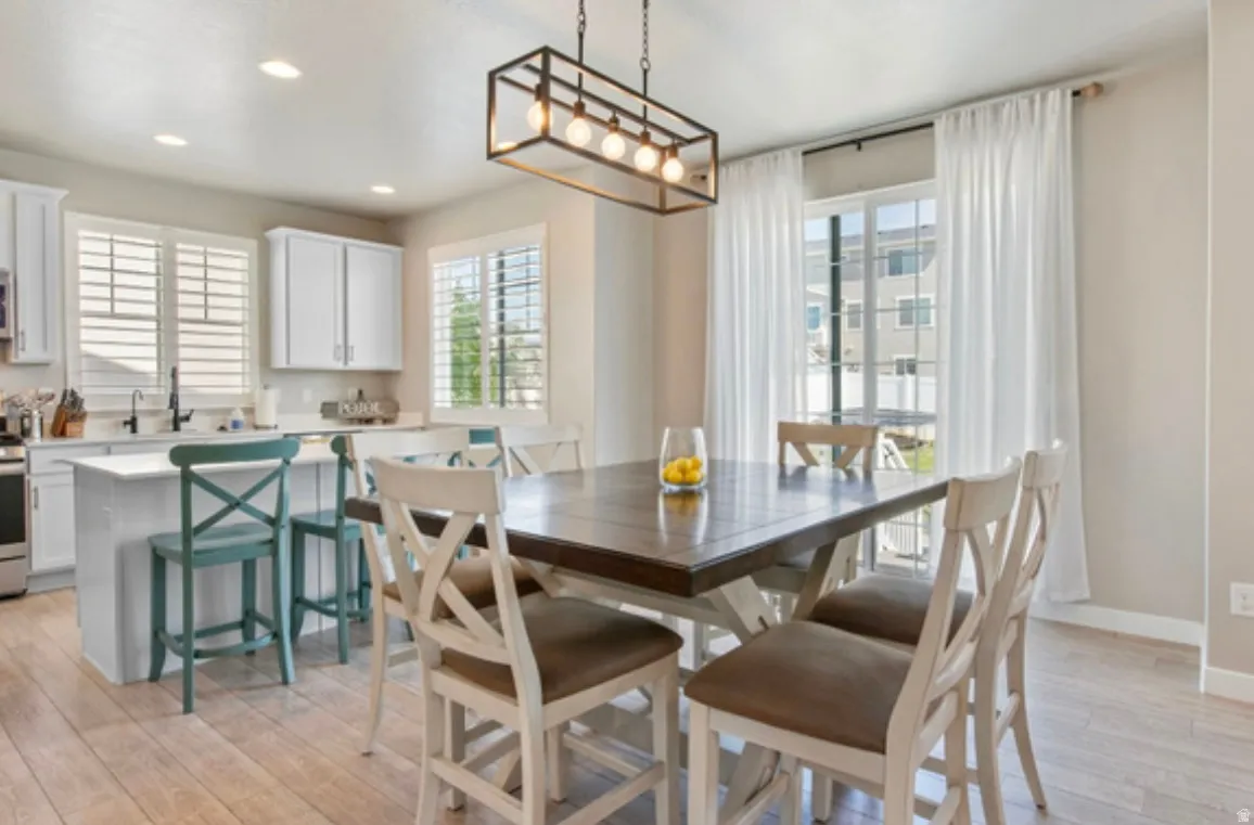 Combined kitchen and dining area featuring light wood-finish flooring, white cabinetry, and a sliding glass door