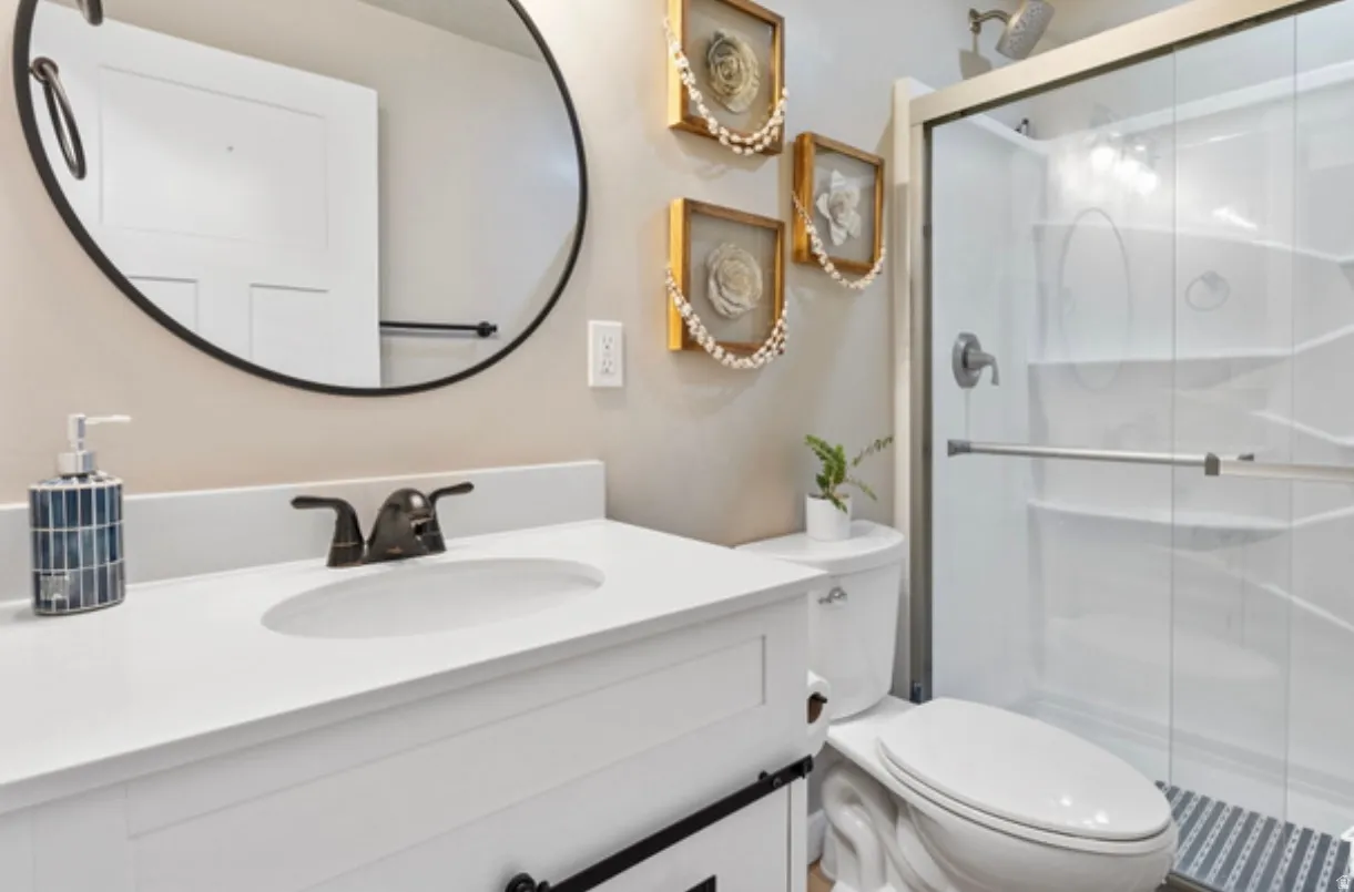 Bathroom featuring a white vanity with an integrated sink, dark bronze-finish faucet, and a round black-framed mirror