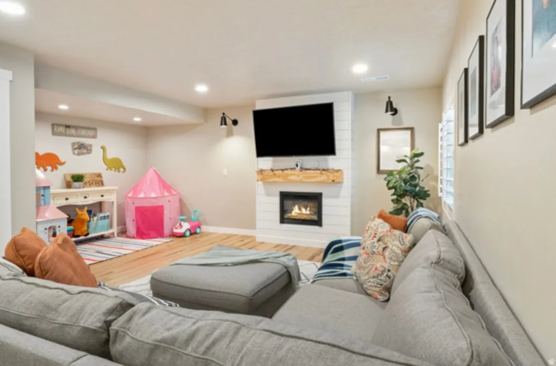 Living area featuring a shiplap-paneled fireplace with a wood mantle, an integrated television mount, and recessed lighting